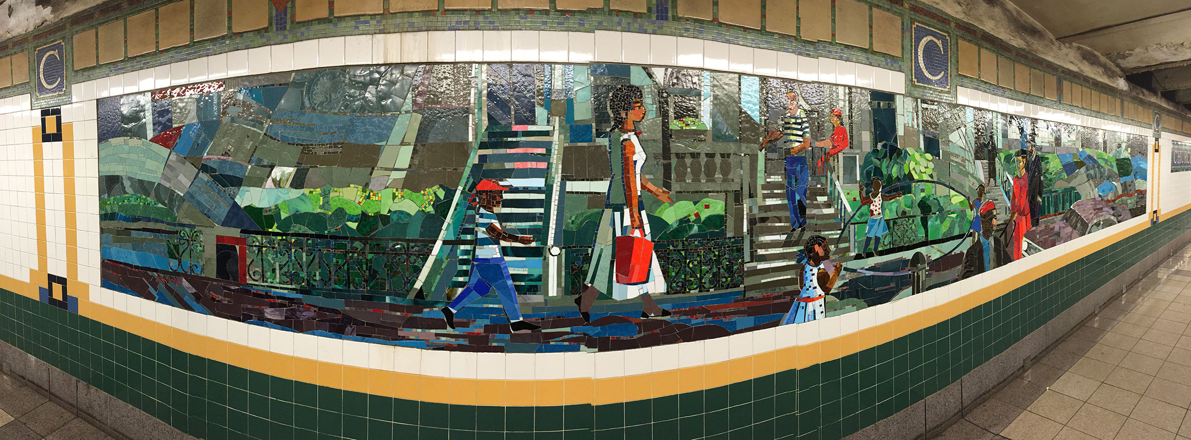 A colorful mosaic mural in a subway station depicting various scenes of people walking, interacting, and enjoying their surroundings. The artwork features individuals of different ages, including children and adults, dressed in a variety of outfits. Green foliage and urban elements like stairs and fences are included, creating a lively and dynamic environment. The tile work displays a mix of vibrant colors and textured patterns, enhancing the visual interest of the space.