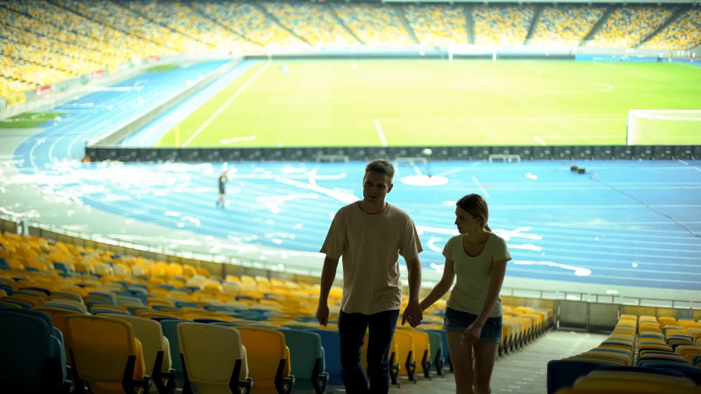 Couple holding hands and walking through the empty stadium after a game.