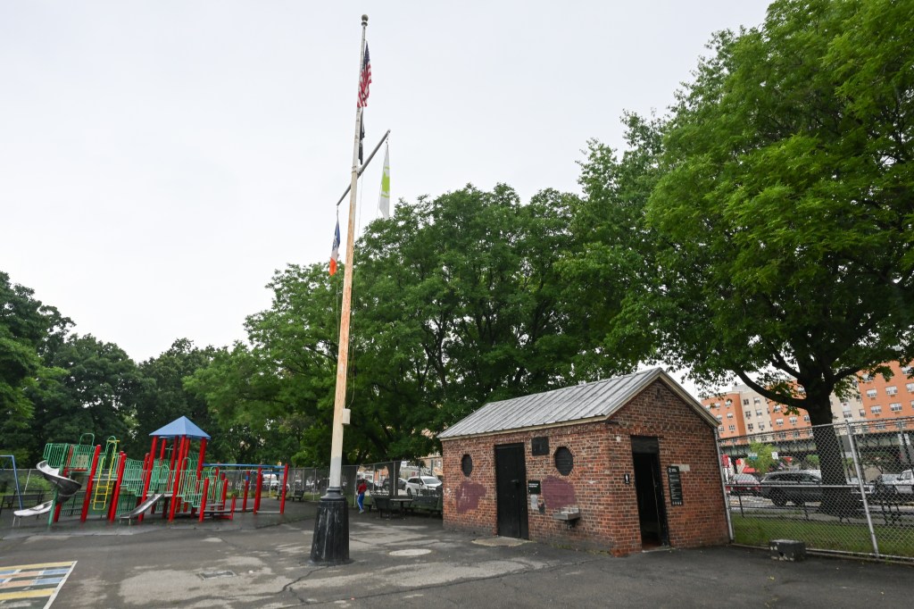A photo of a small brick bathroom at 2222 Bronx Park East. Behind you see a playground and green trees.