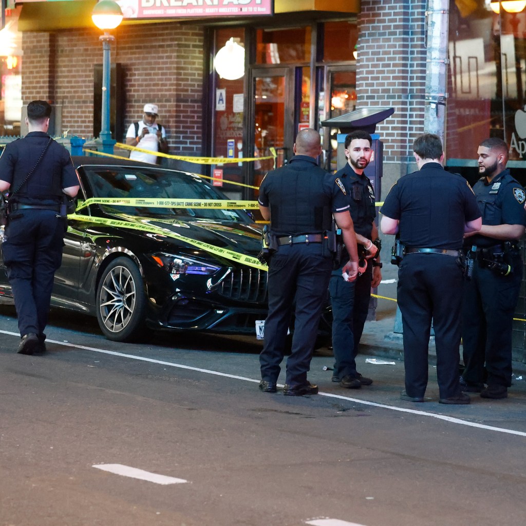 Police investigate a crime scene where a black car is cordoned off with yellow tape.