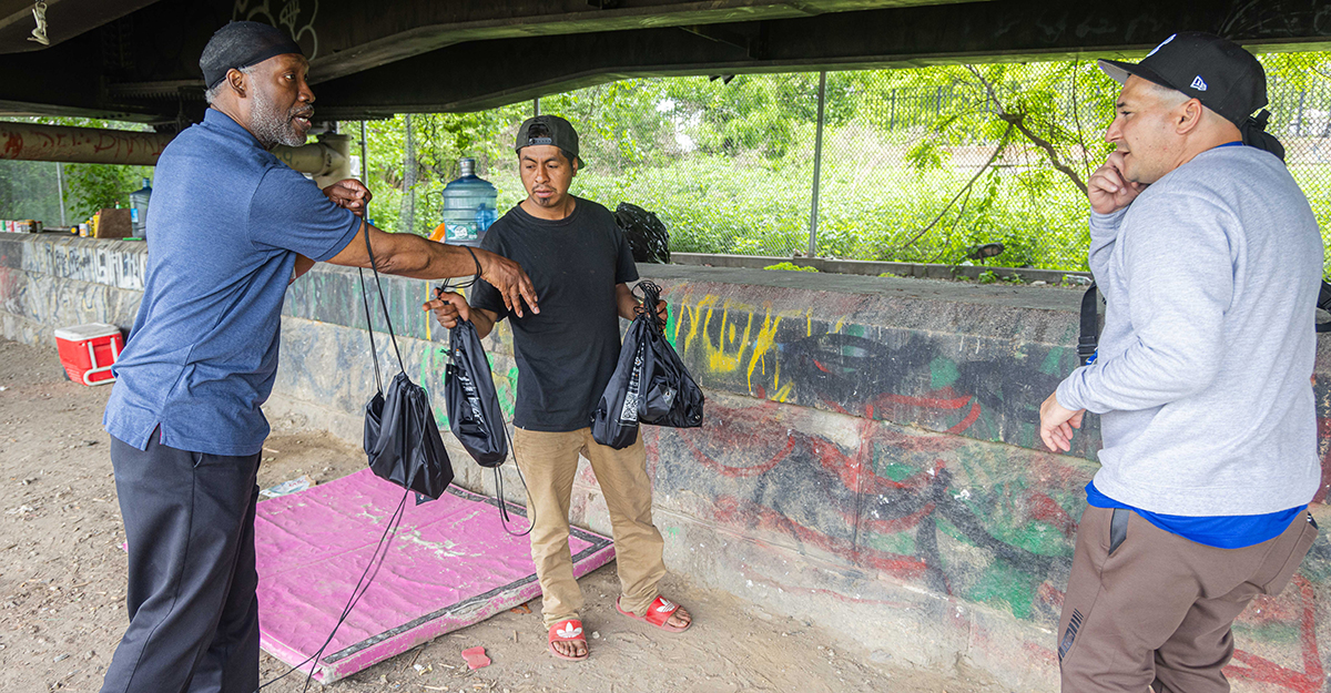 Andre offers resource bags to one of the encampment residents who only speaks Spanish. Jose who is bilingual, communicates with the individual in Spanish – offering to connect him to a shelter if he needed it, as well as medical services available to him at nearby NYC Health + Hospitals/Lincoln. (1/6)