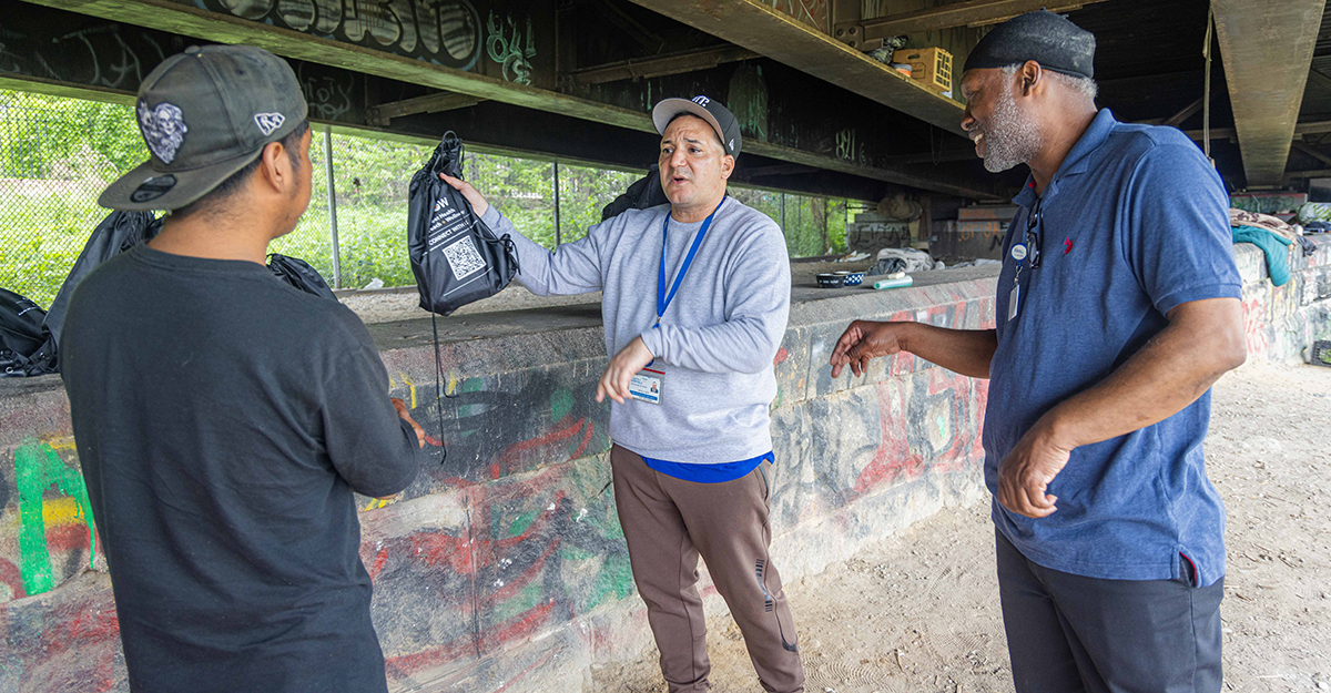 Andre offers resource bags to one of the encampment residents who only speaks Spanish. Jose who is bilingual, communicates with the individual in Spanish – offering to connect him to a shelter if he needed it, as well as medical services available to him at nearby NYC Health + Hospitals/Lincoln. (2/6)
