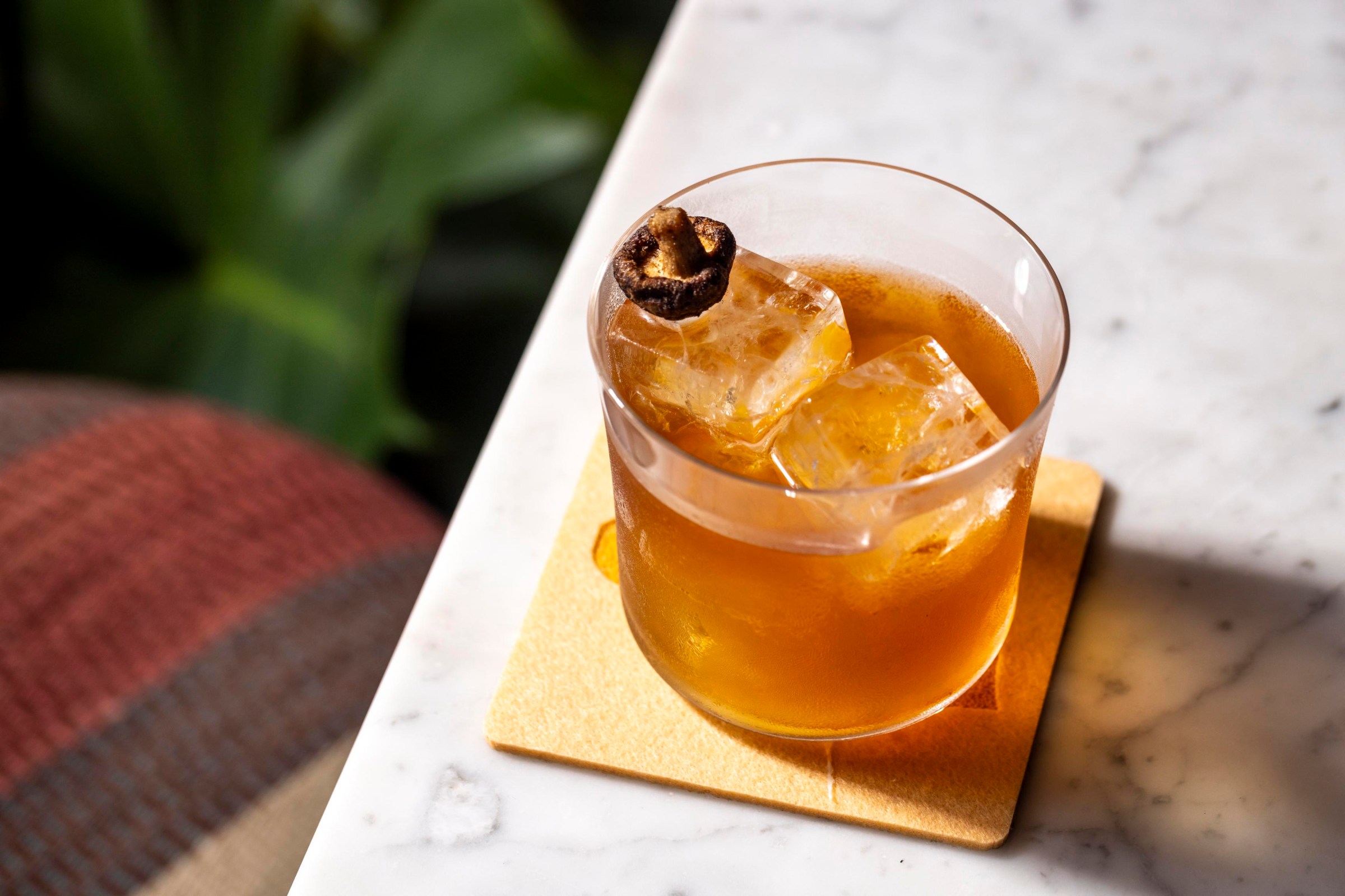 A short cocktail with a mushroom on the ice.
