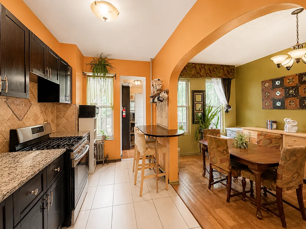 kitchen with orange walls and arched doorway into dining