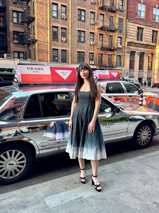 Woman in Paloma Platforms standing next to a reflective taxi with a Prada ad.