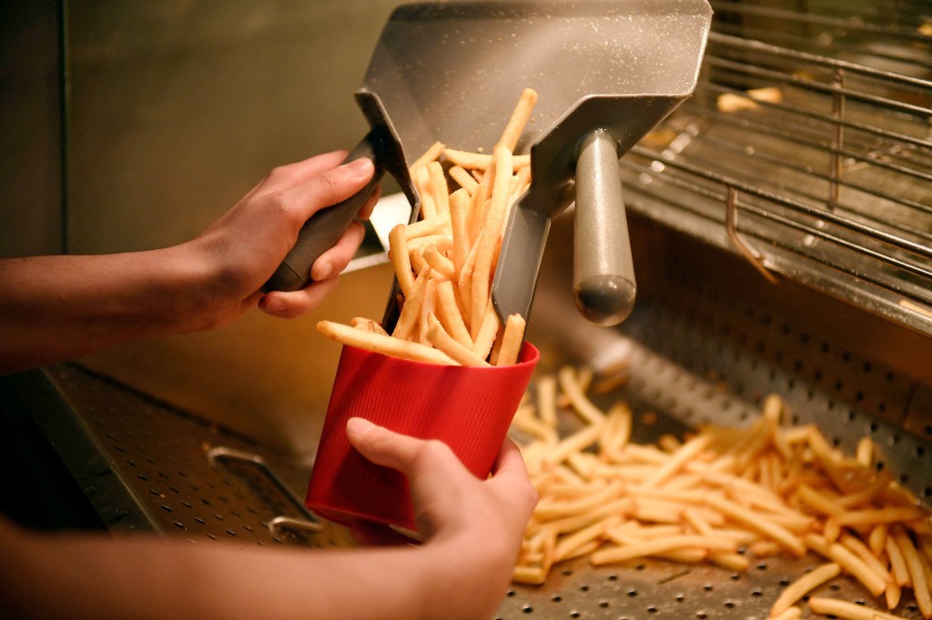 A photo of a McDonald's employee serving fries. 
