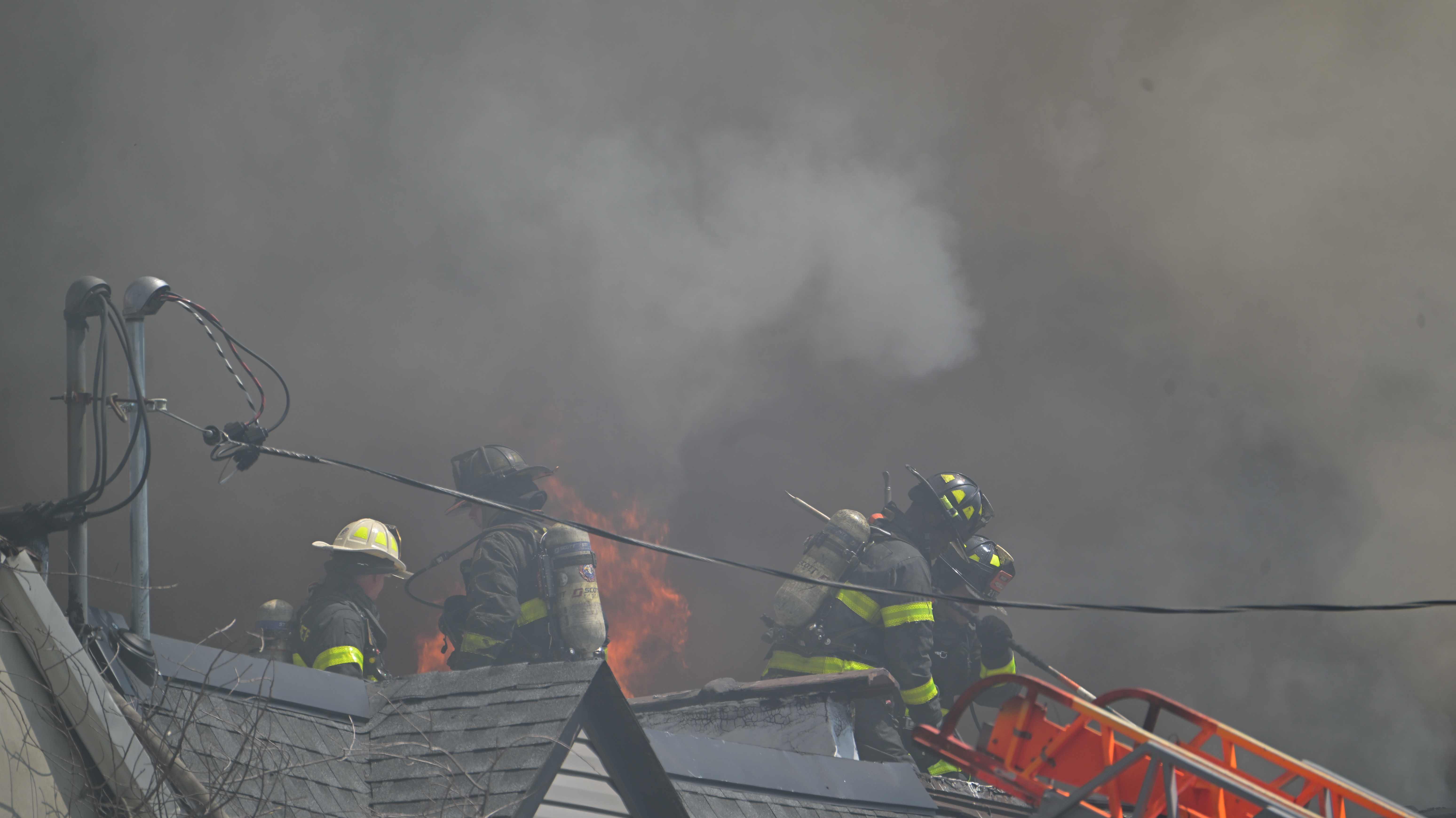 Rescue 4 firefighters on the roof of the main fire building at 132-15 41st Rd. that extended to two neighboring homes. 