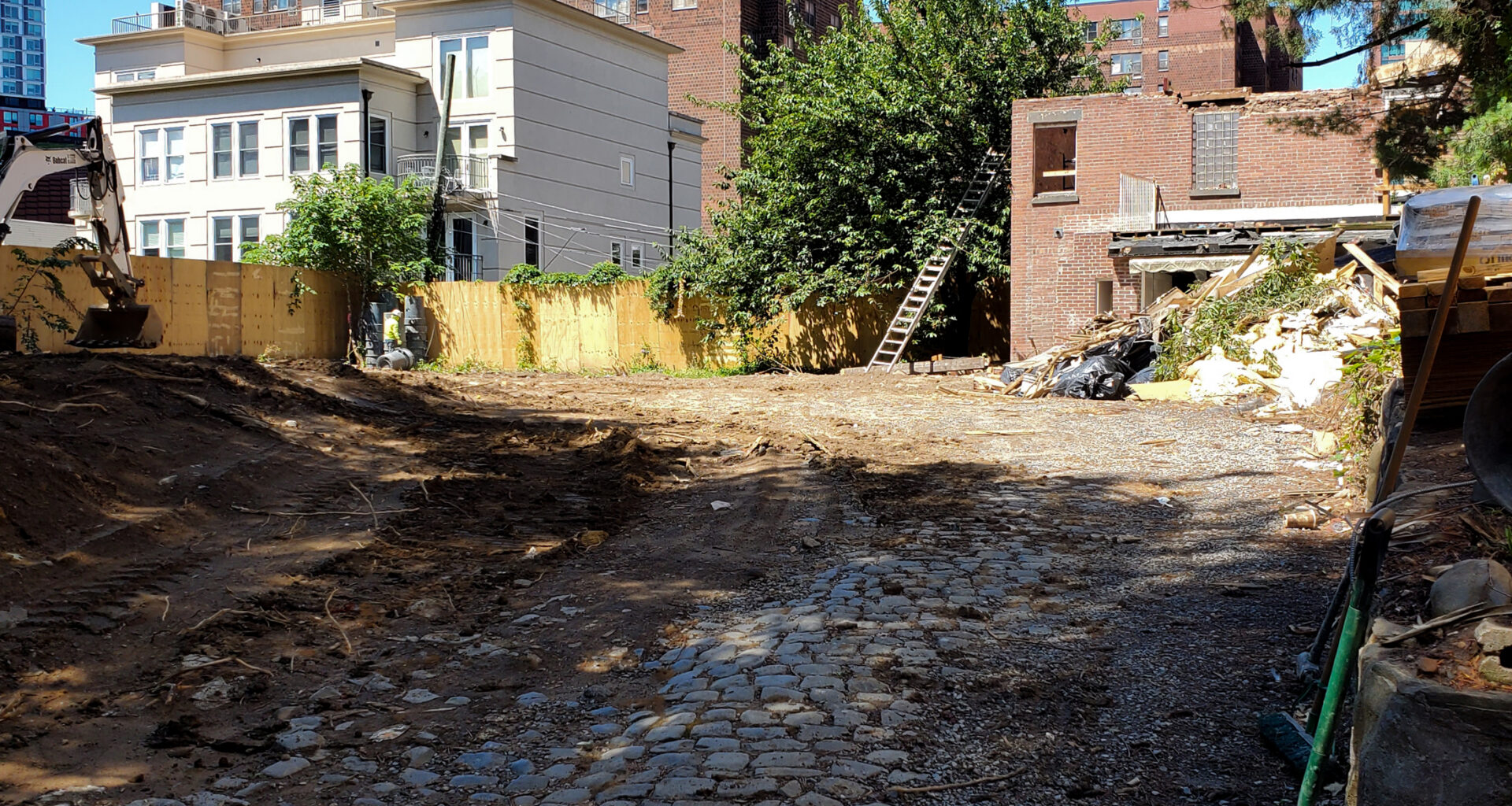 site of demolished house with a brick garage in process of being demolished