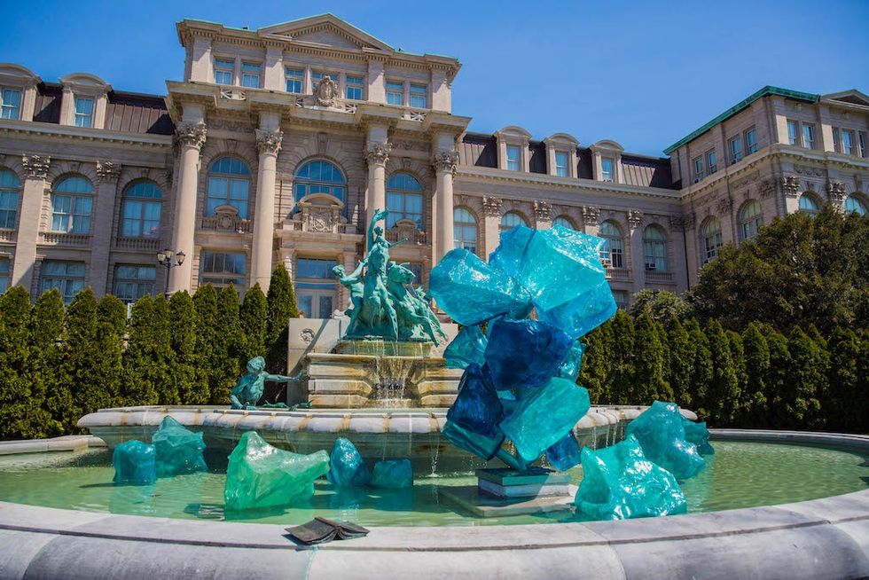 Fountain with large blue glass sculptures in front of a grand building at New York Botanical Garden