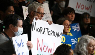 People hold up signs saying "Moratorium Now!" at an anti-AI data center rally in Albany, New York in May 2026.