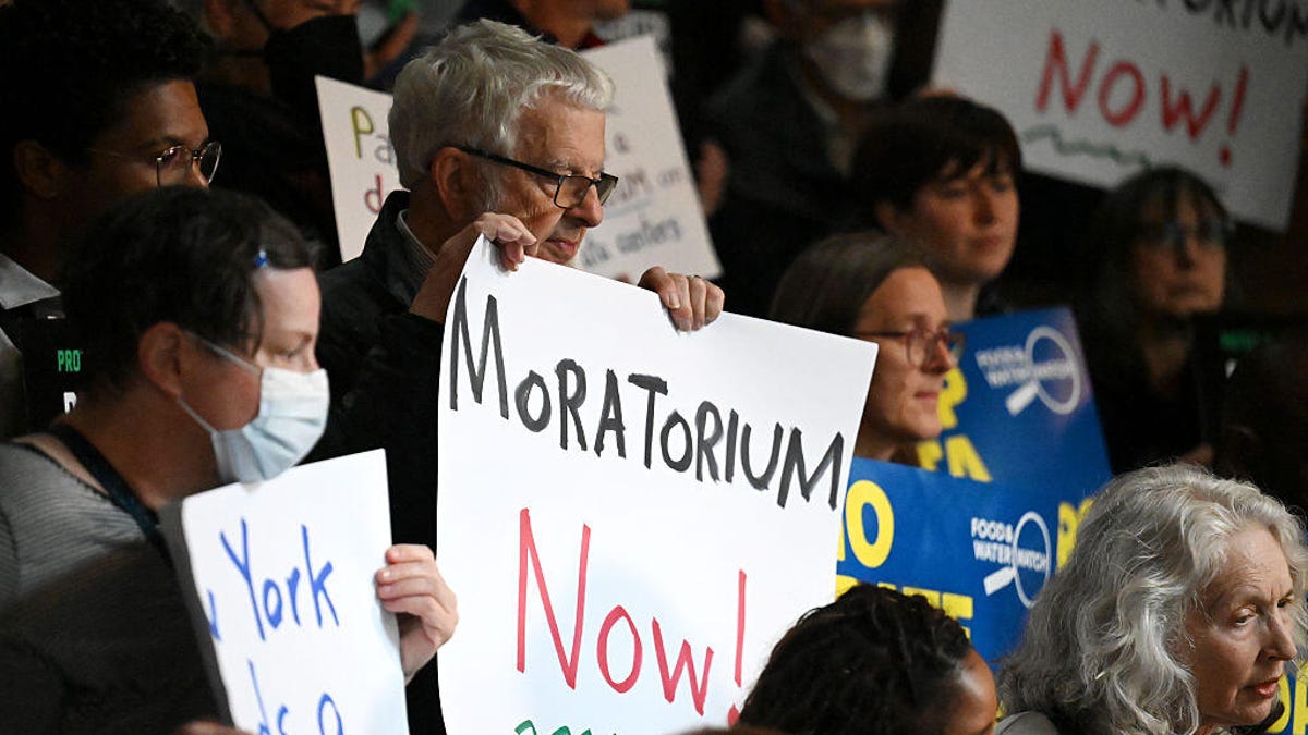 People hold up signs saying "Moratorium Now!" at an anti-AI data center rally in Albany, New York in May 2026.