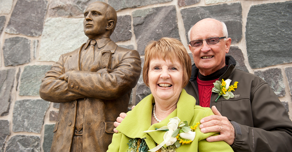 Jill and Terry Martin stand in front of the Terry Martin statue at the entrance of Roos House.
