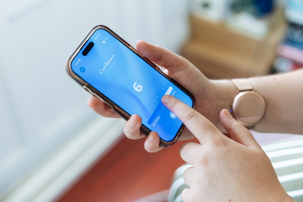 Hands holding a smartphone displaying the "Cool Balance" app, set to a cooling level of "6" with "08:24 remaining."
