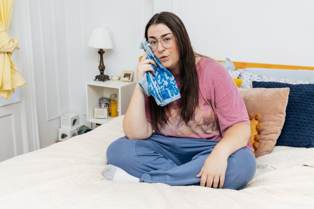 McKenzie Beard on her bed, wiping her face with a blue cloth.