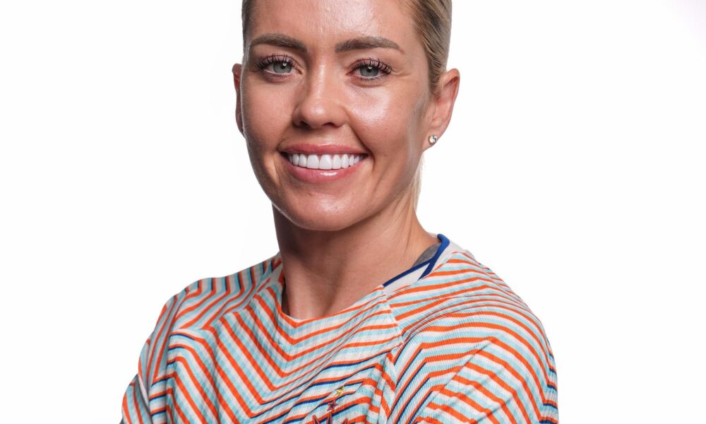 A player smiles and poses for a photo in a multicolored NJ/NY Gotham FC jersey