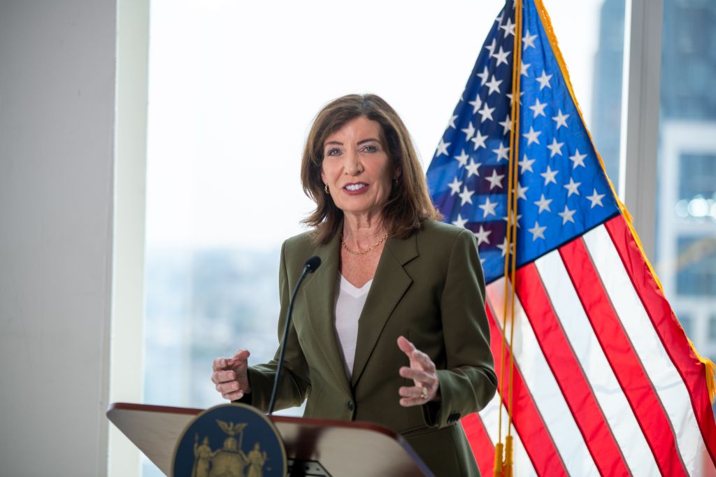 New York Governor Kathy Hochul speaks at a podium with an American flag behind her.