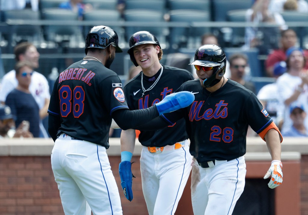 New York Mets players Tyrone Taylor and Luis Robert Jr. celebrate with another player.