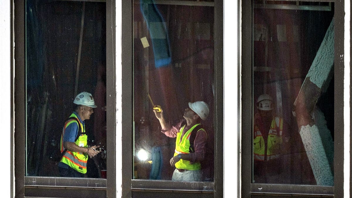 Workers inspecting buckled support beams inside a New York City high-rise