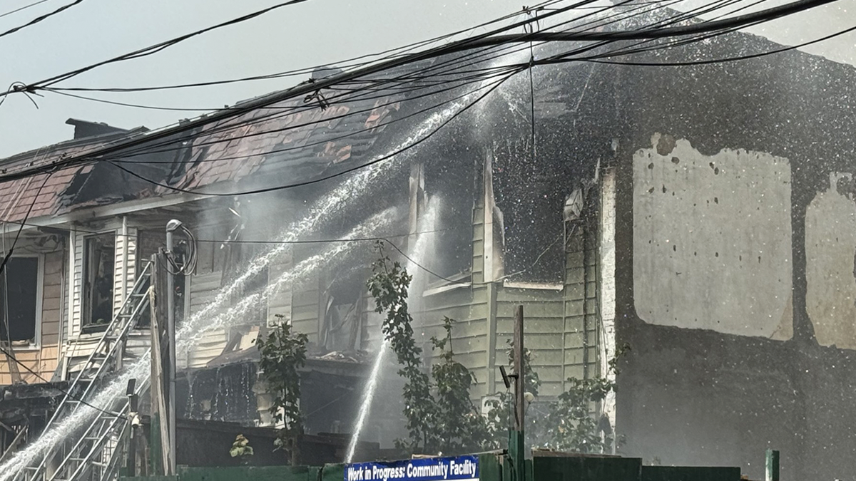 Firefighters direct multiple water streams onto a heavily damaged residential building as crews work to extinguish a large structure fire.