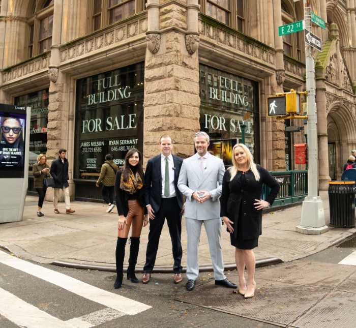 four people standing in front of a building that is for sale