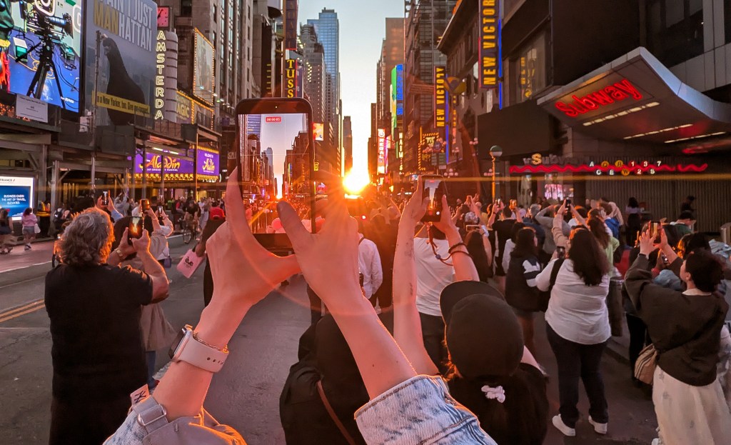 People photograph Manhattanhenge, where the sunset aligns perfectly with the street grid.