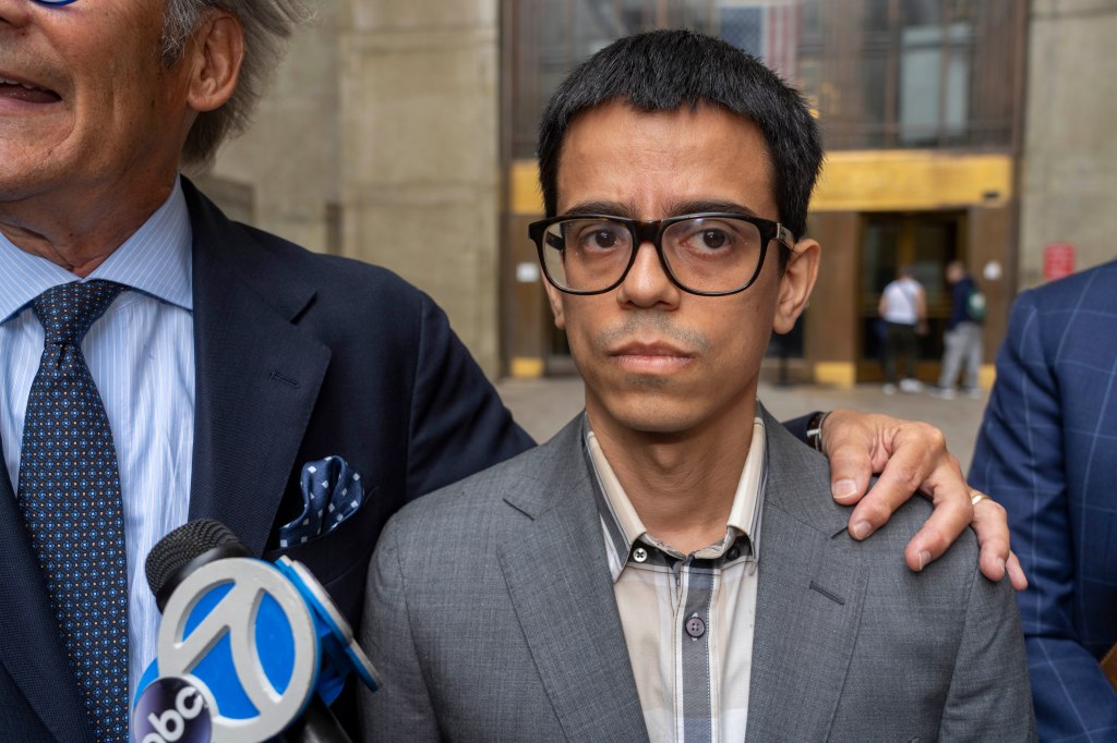 Police Officer Quilbvio Espinal, 35, stands with his lawyer Robert Gottlieb, in front of microphones.
