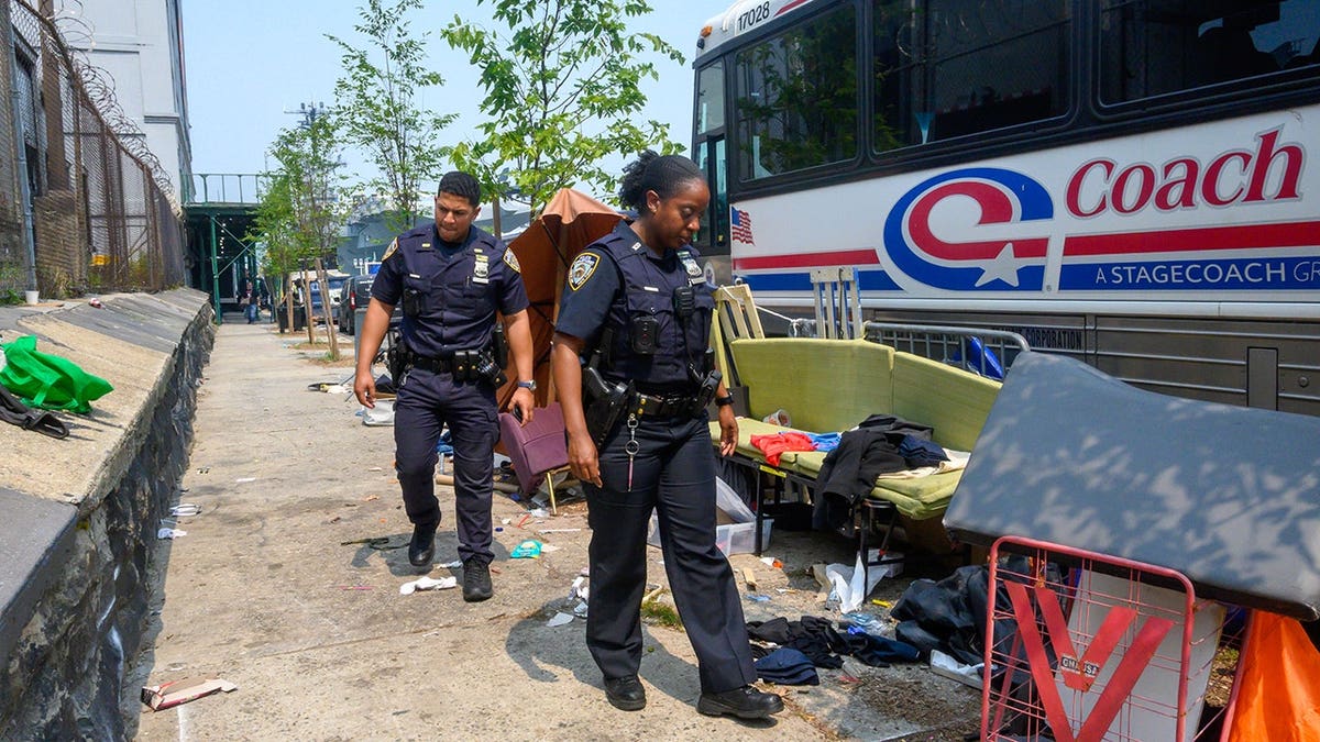 Police walk down the streets filled with homeless encampments
