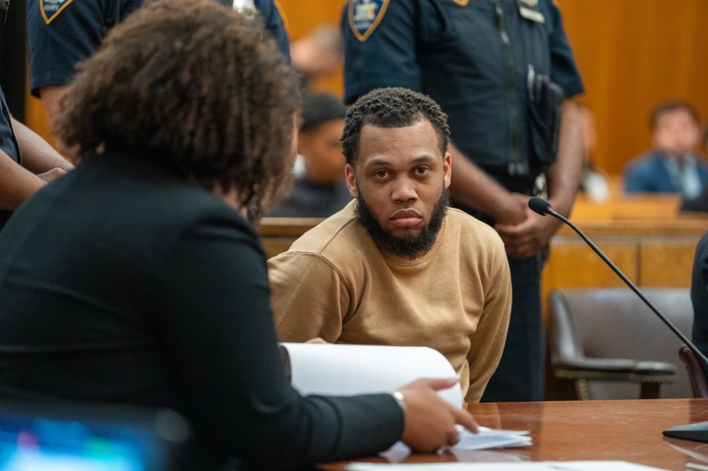 Donovan Murphy, seated at a table in a courtroom, looks towards a person whose back is to the camera.