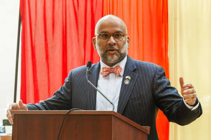 man in suit and bowtie at a podium