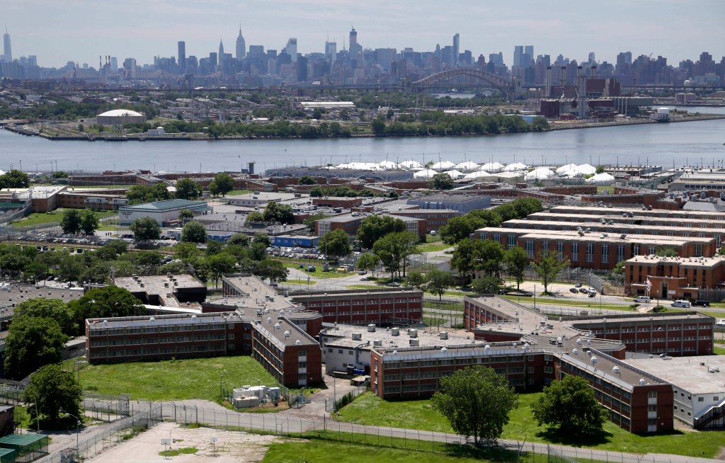 Aerial view of the Rikers Island jail complex with the Manhattan skyline in the background.