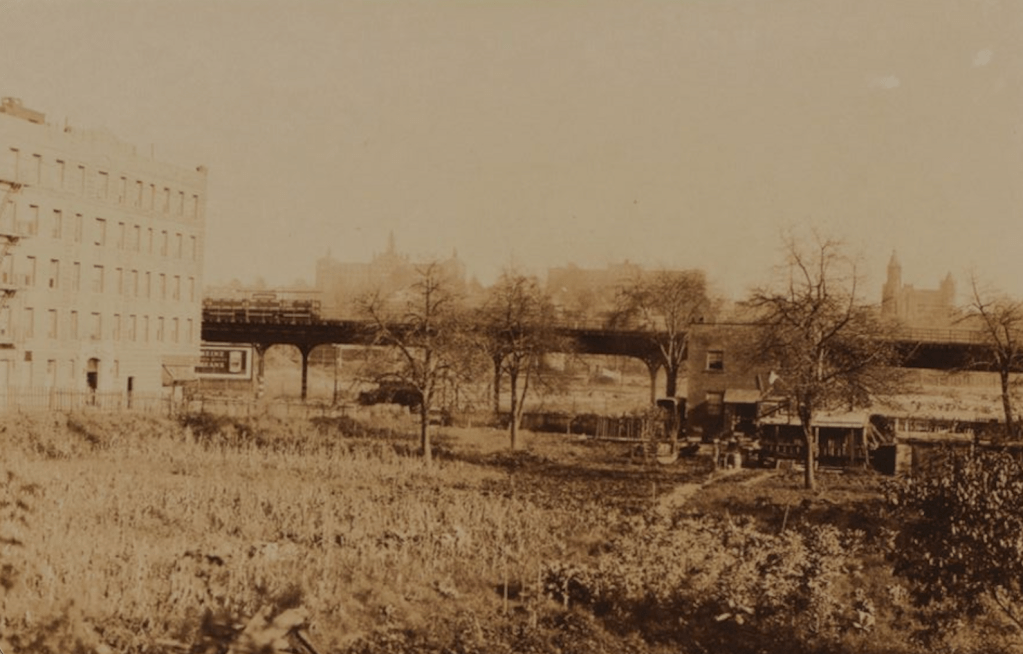 Historic view of an urban landscape with a building on the left, a bridge in the center, and a garden area in the foreground, all depicted in sepia tone.