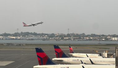 LaGuardia Airport runway with an American Airlines plane taking off and several delta planes waiting on a runway