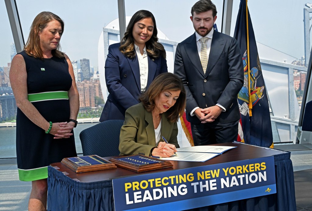 Governor Kathy Hochul signing an executive order to pause AI data center construction, with Julie Tighe, State Senator Kristen Gonzalez, and Coner Eckert in the background.