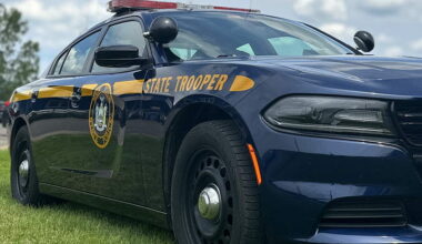 The side of a New York State Police car sitting on lawn