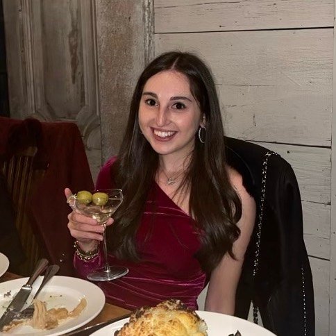 Stefanie Rock, 29, holding a martini glass, smiling at a restaurant.