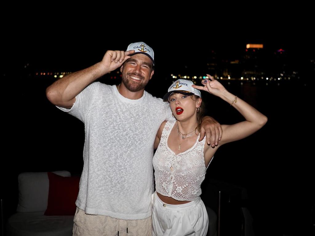 Travis Kelce and Taylor Swift wearing matching "Captain" and "First Mate" hats.