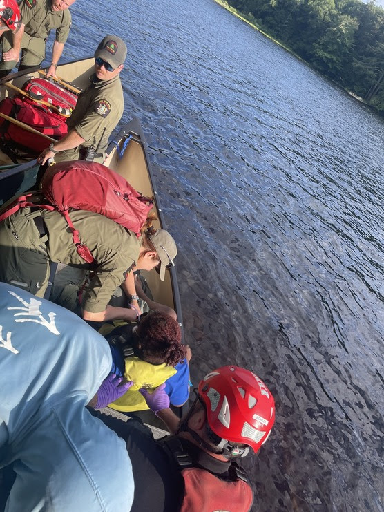 Forest rangers stand on a boat with a patient