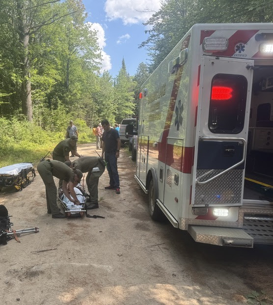 An ambulance is parked with medics and a patient next to it