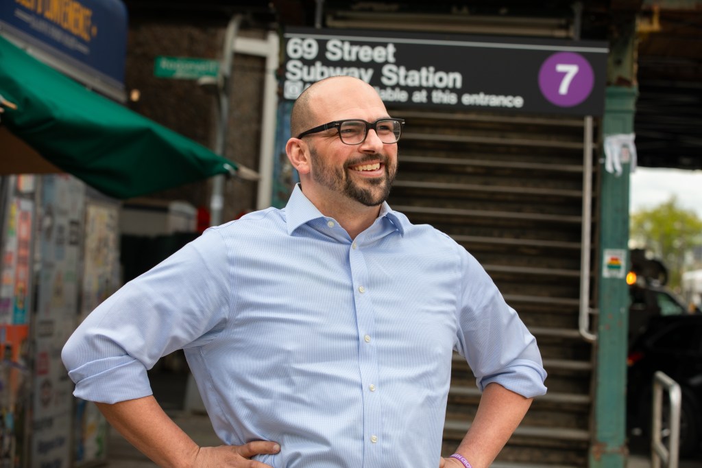 Patrick Martinez smiling in front of the 69 Street Subway Station.