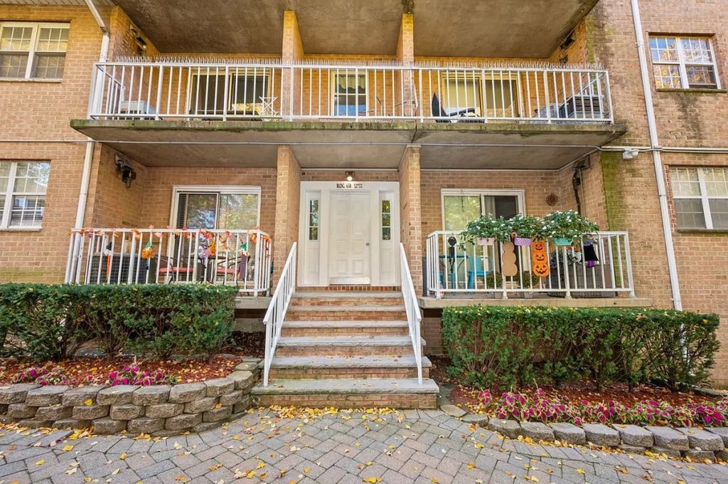Building entrance with brick stairs and Halloween decorations on the balconies.