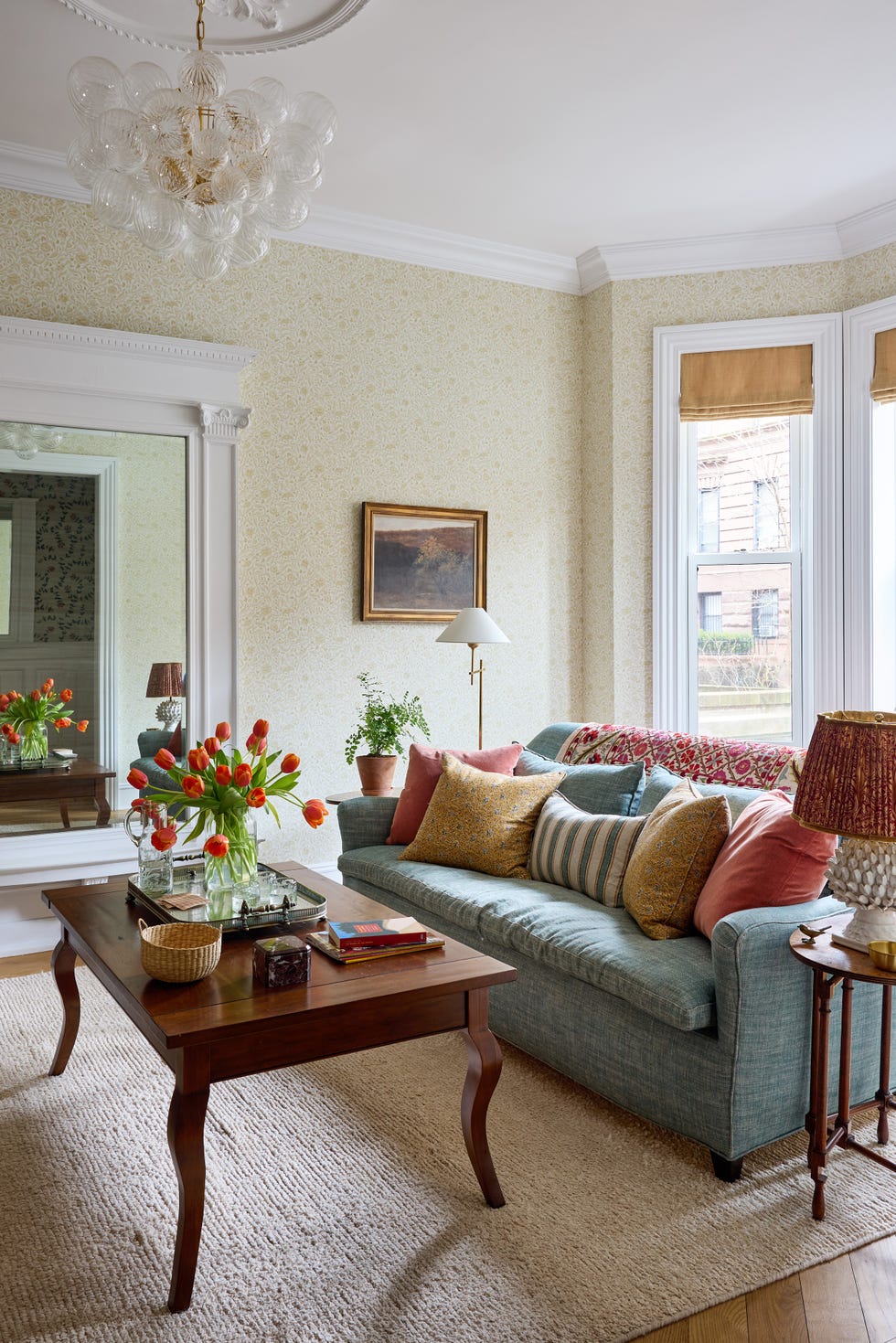 Brightly decorated living room featuring a cozy couch with colorful pillows, a wooden coffee table, and a vase of tulips.