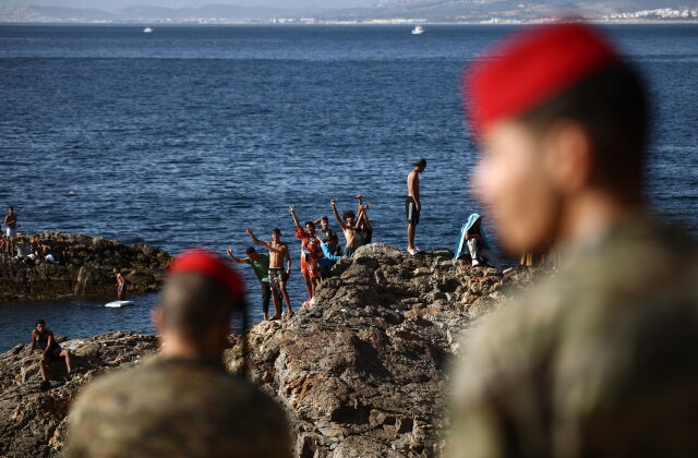 TOPSHOT - Members of the Spanish Army's 'Regulares' infantry forces watch a group of migrants near the border post of the Spanish enclave of Ceuta on August 2, 2026. At least 72 people died during last week's mass influx of migrants into Spain's Ceuta enclave, when tens of thousands of people mostly swam around the border post from Morocco, local officials said today. Most of the estimated 60,000 people who rushed into Spain's north African territory have returned to Morocco since the territory's largest mass migrant crossing. (Photo by Henry NICHOLLS / AFP via Getty Images)