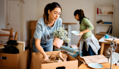 Young woman and her friend packing their belongings while preparing to move out of apartment.