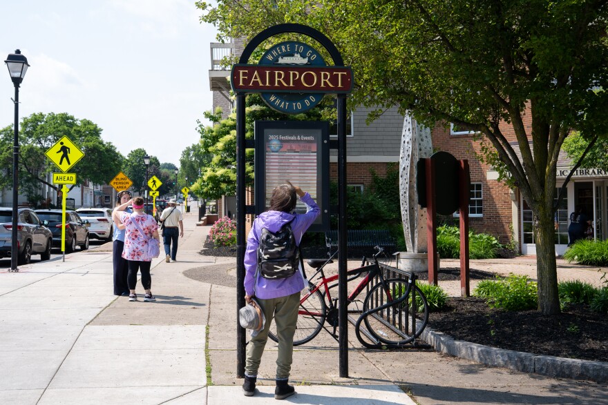 A woman looks at a festival and events listing posted in the village of Fairport in this 2025 file photo.