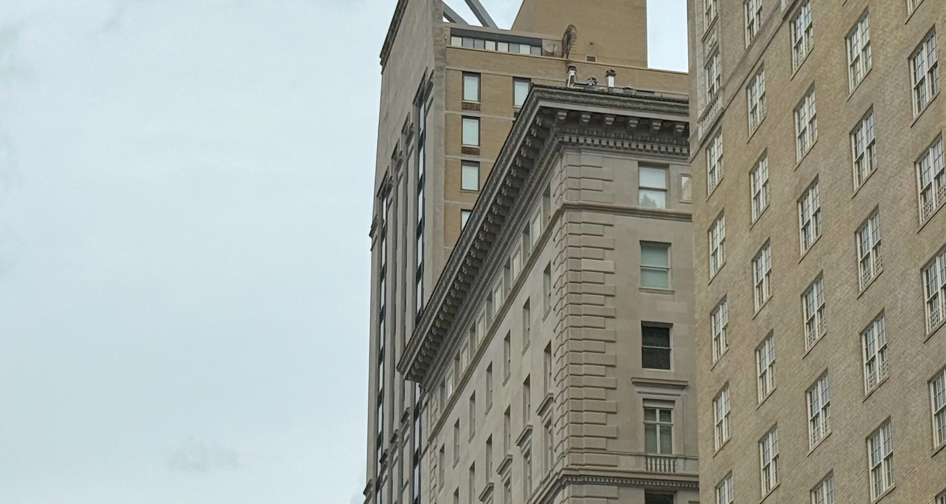 A view of two buildings in an urban area, showcasing distinct architectural styles, with a cloudy sky in the background.