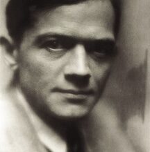 A black and white portrait of a man with short hair and a serious expression, wearing a suit and tie.