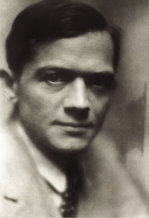 A black and white portrait of a man with short hair and a serious expression, wearing a suit and tie.
