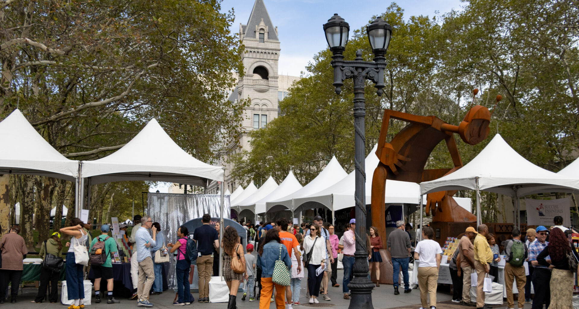 book booths with white tent tops around columbus park with the post office in the background
