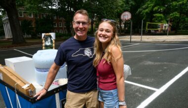 man with navy blue Queens University teeshirt on stands with girl with long blond hair wearing shorts and a maroon tank top.