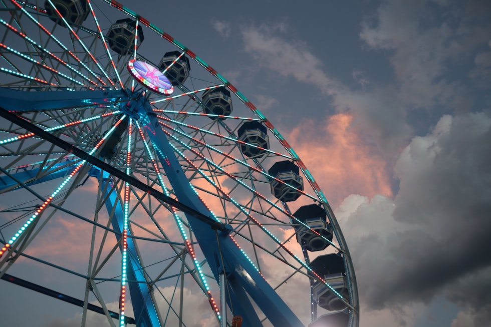 a ferris wheel is lit up against a cloudy sky